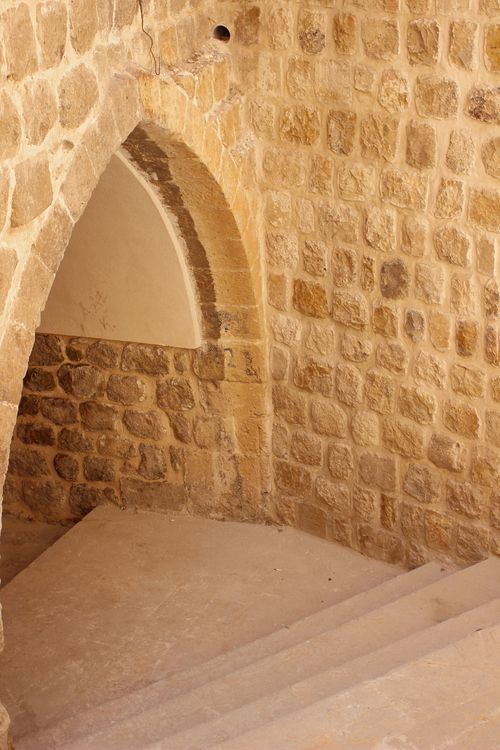 Free A vintage stone staircase with an arched entryway, featuring textured walls. Stock Photo
