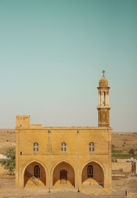 A picturesque historic stone church with arched windows and a tower under a clear sky, perfect for travel and architecture themes.