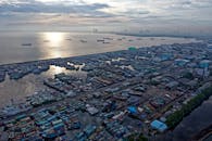 日出时，雅加达的港口展现在眼前，可以看到船只、工业建筑和城市景观