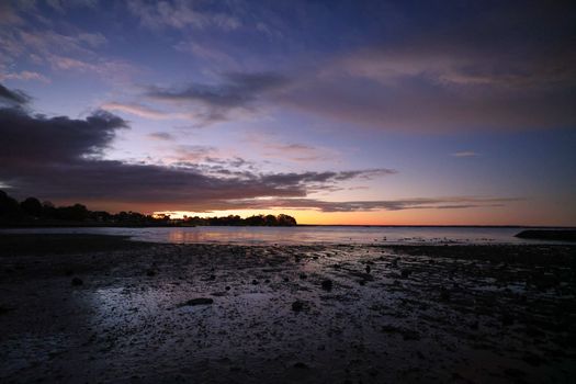 Peaceful sunset at Stamford shoreline with colorful sky and calm sea.