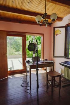 A cozy music studio with microphone, keyboard, and natural light from large windows.