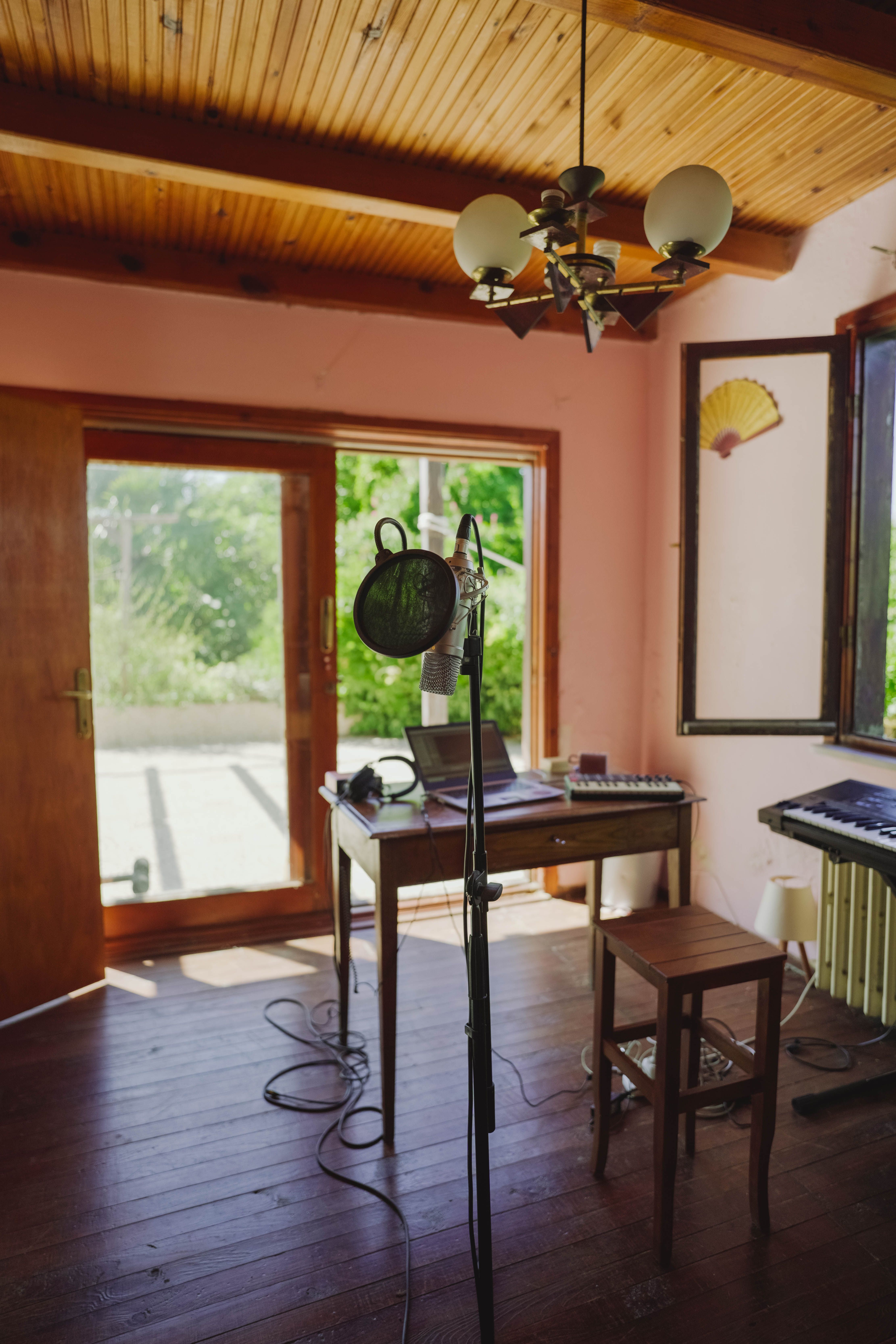 A microphone and laptop on a desk beside a glass door