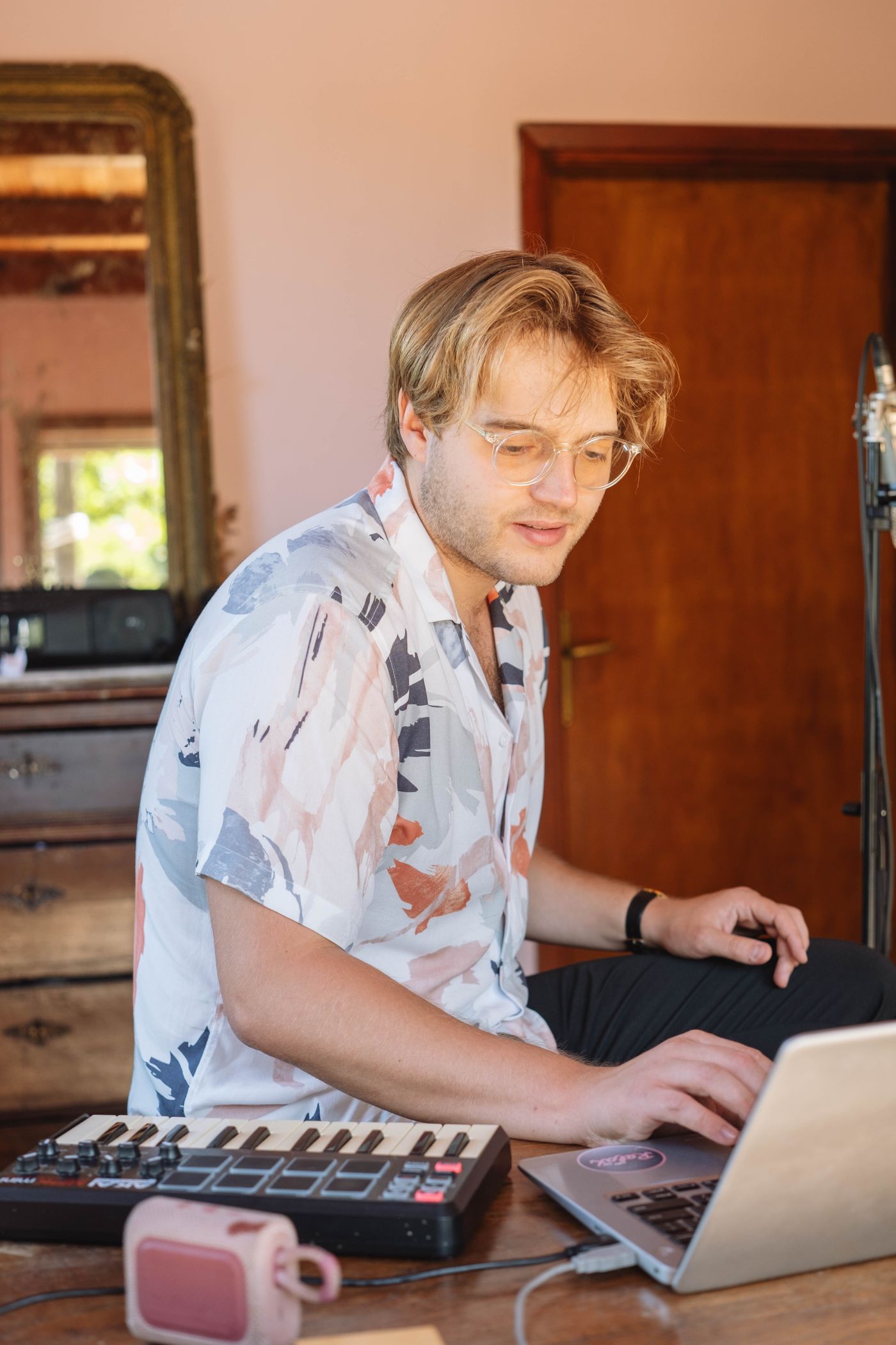 Musician using a keyboard and laptop in a home studio to manage music and website assets