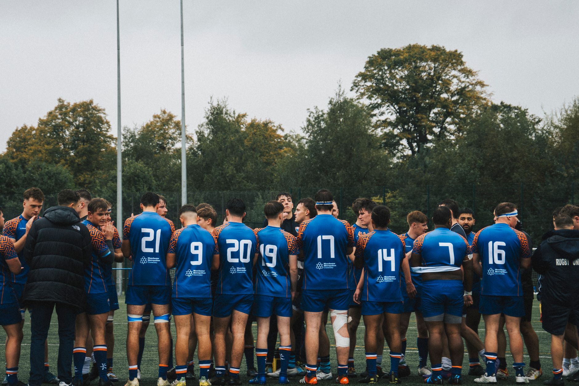 A rugby team in blue jerseys huddled together on a field, showcasing teamwork and strategy.