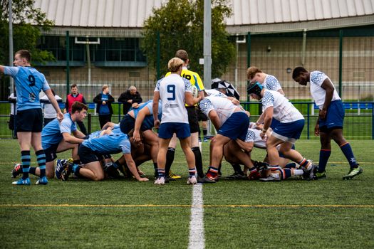 Rugby players in action during a competitive daytime match on a sports field.