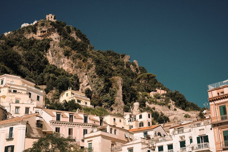 Pastel hillside town beneath a wooded ridge, photo by Alina Chernii on Pexels
