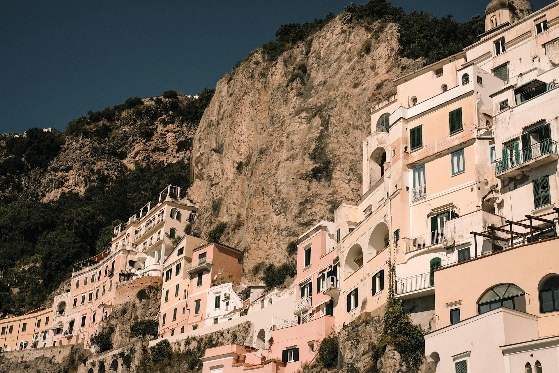 Charming cliffside houses in a coastal Italian town bathed in warm sunlight.
