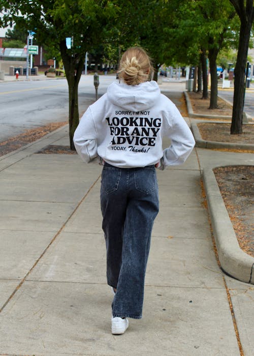 Back View of a Blonde Wearing a Hoodie with a Script, Walking on a Pavement in an Alley