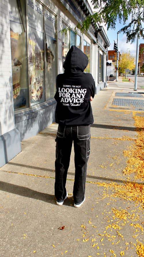 Back View of a Person in a Hoodie Standing on the Sidewalk 