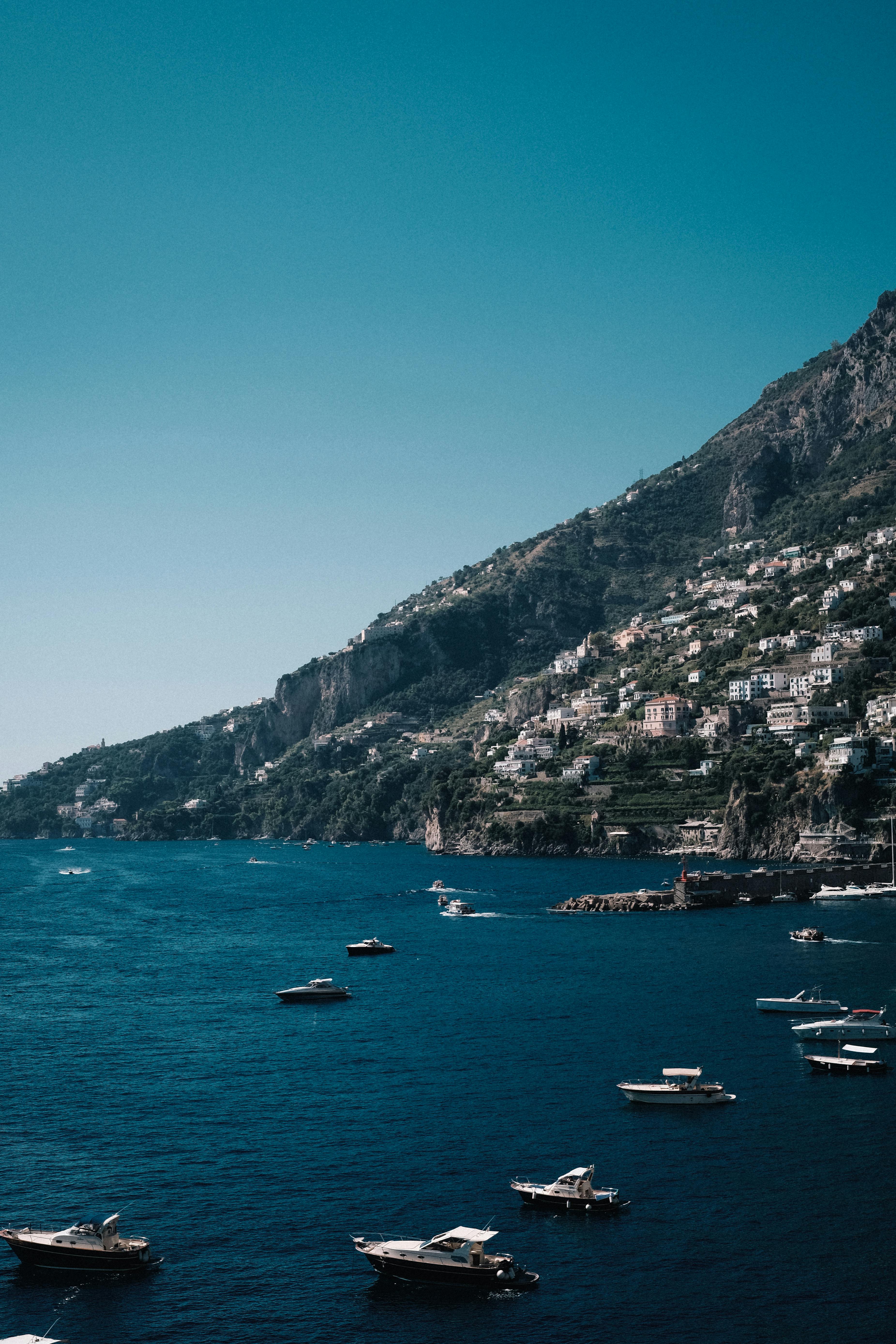 Stunning aerial view of boats near a coastal town on the picturesque Amalfi coastline.