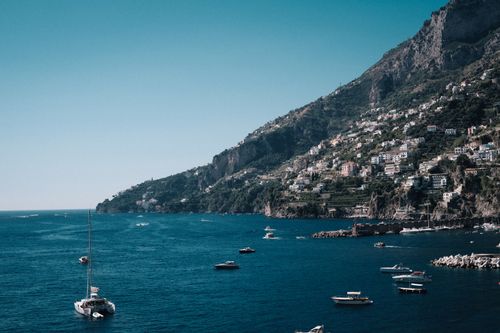 Free A stunning view of the Amalfi coastline featuring boats and rugged cliffs under a clear sky. Stock Photo