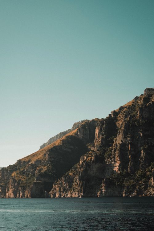 Free Breathtaking view of a rocky coastline under a clear blue sky. Perfect for nature enthusiasts. Stock Photo