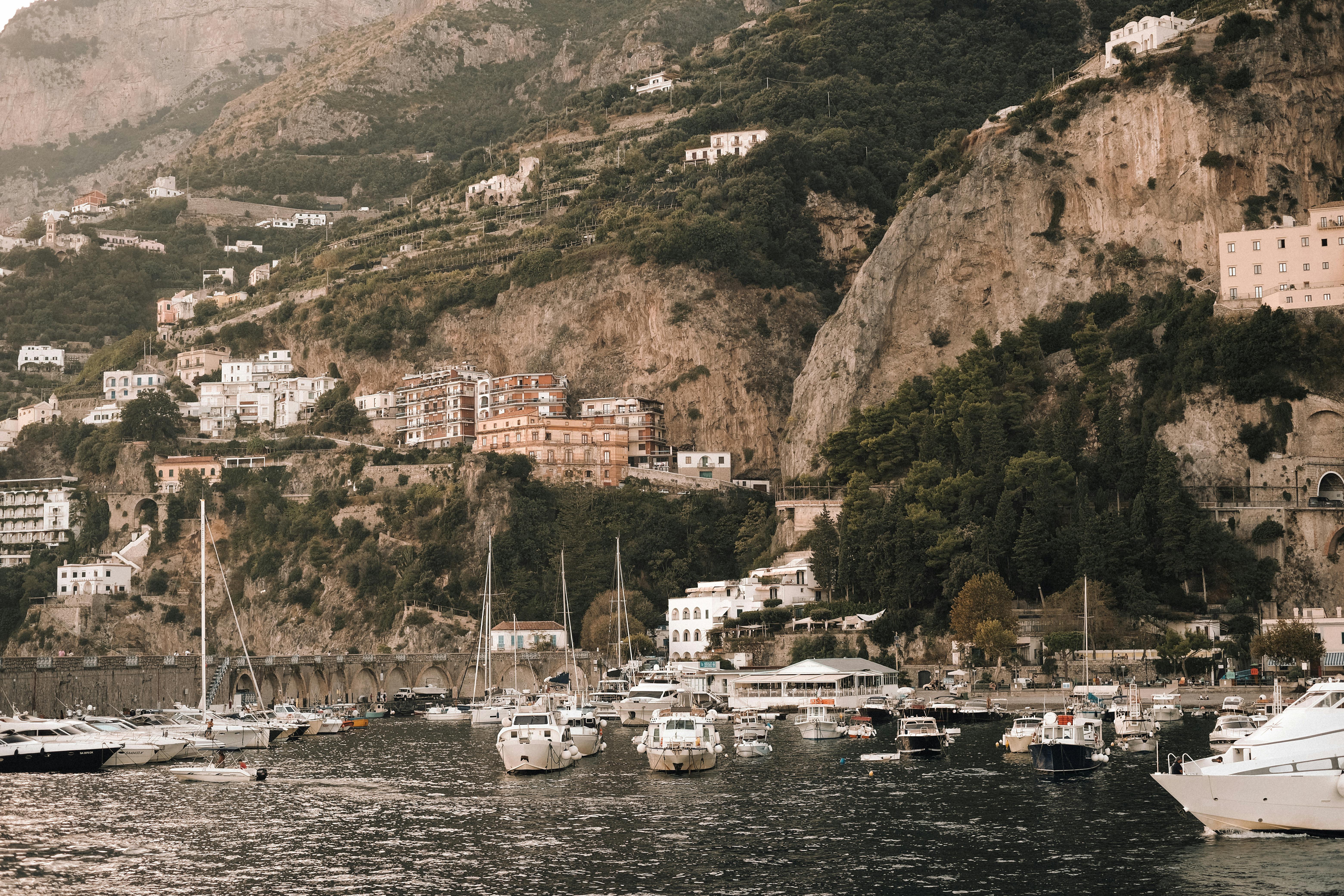 Picturesque Amalfi Coast with yachts and charming hillside buildings at the seashore.