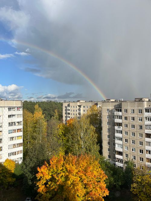 Free A vibrant rainbow arches over autumn-colored trees and apartment buildings in Minsk, Belarus. Stock Photo