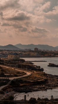 A scenic view of Murcia's coastline with urban skyline and mountains at dusk.
