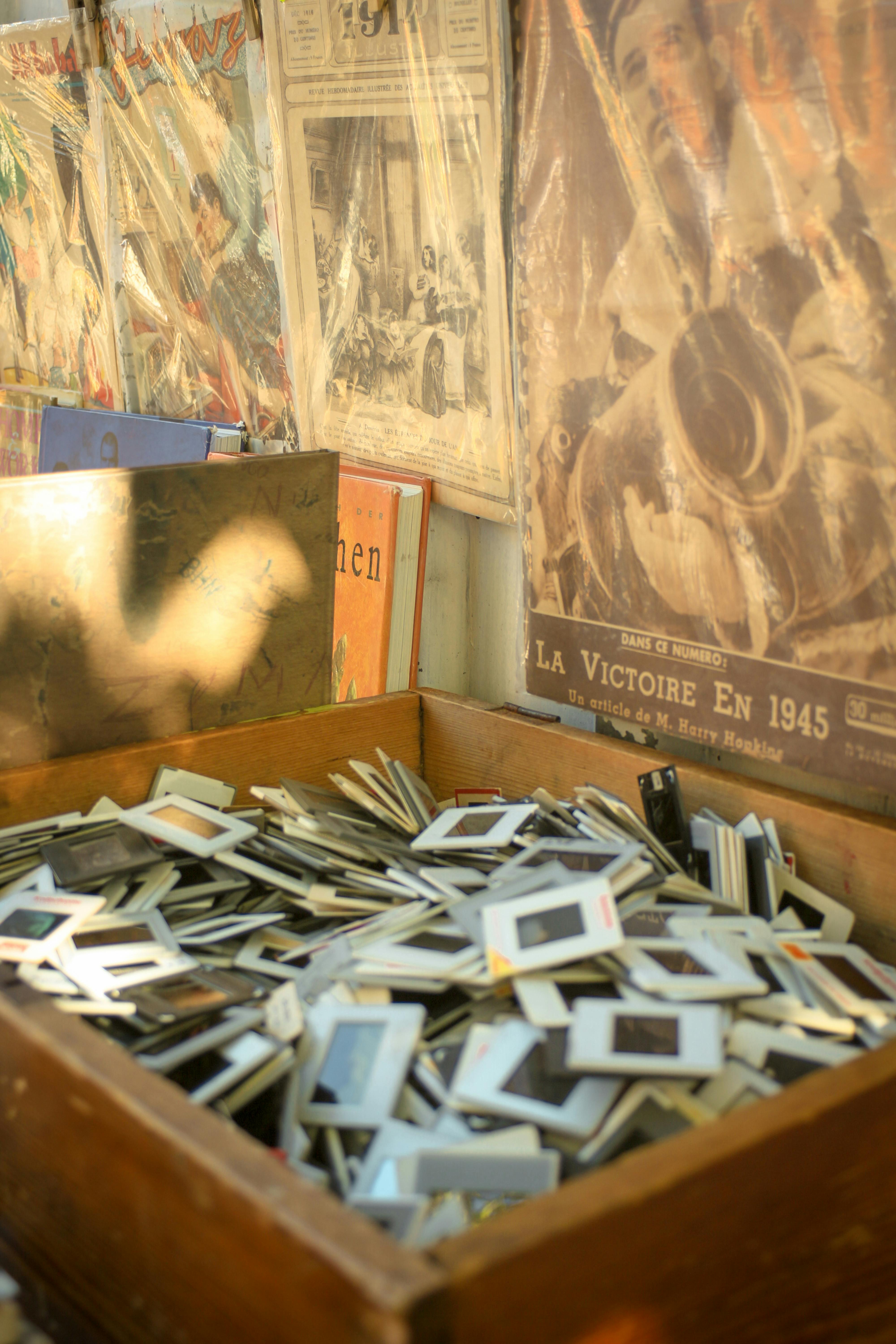 A wooden box filled with vintage slides surrounded by nostalgic antique posters, evoking a sense of history.