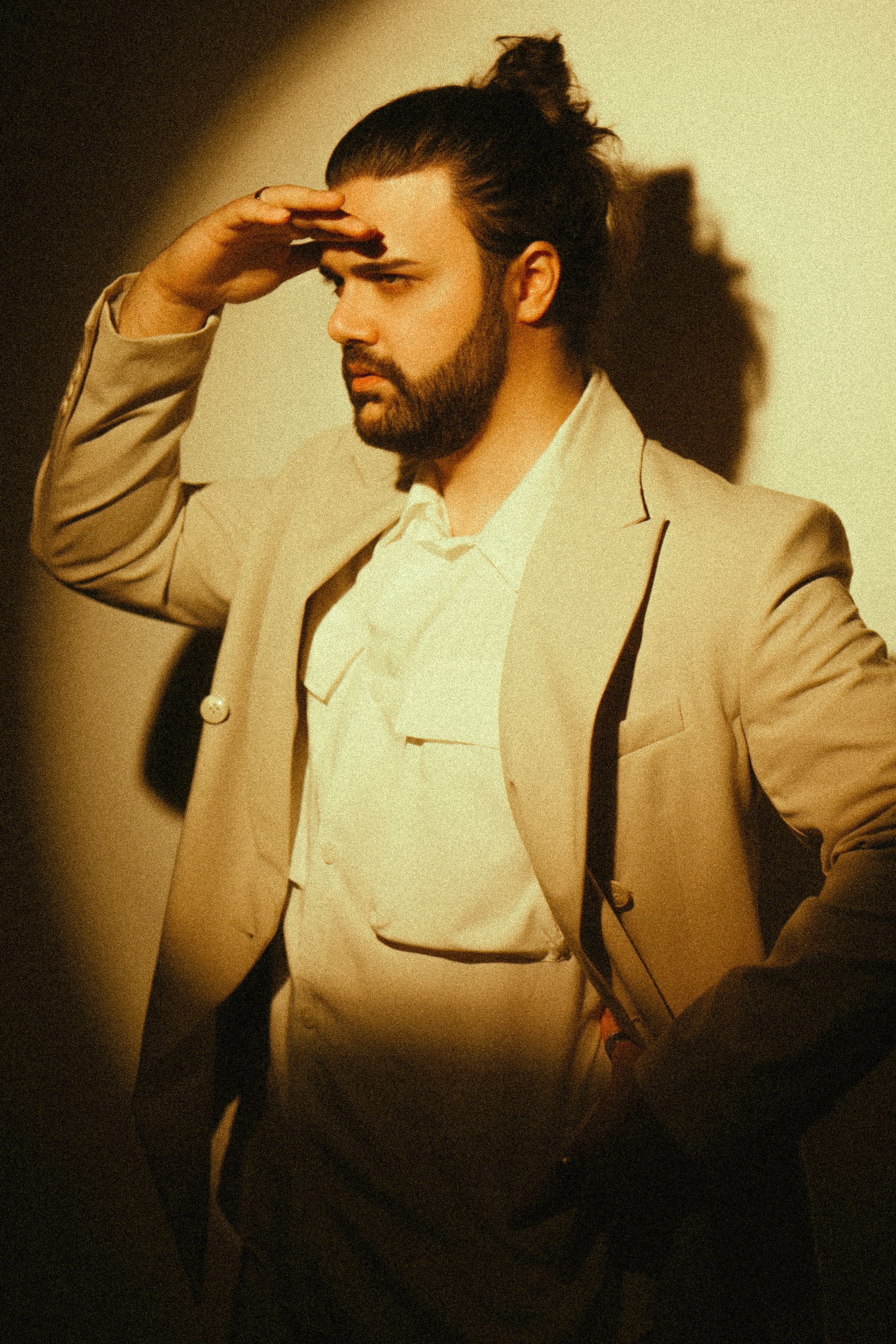 Portrait of a fashionable man in a beige jacket with artistic shadow effects.