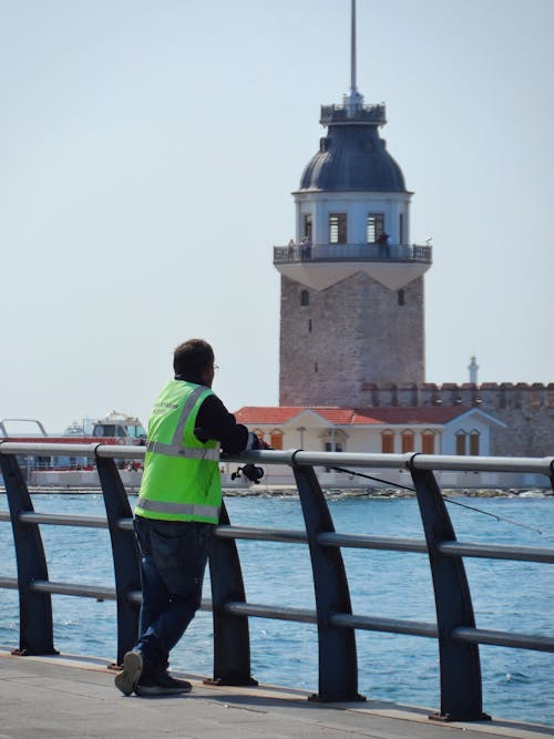 Worker Fishing on Sea Shore in Istanbul with Kiz Kulesi behind