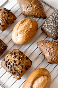 A variety of artisan breads with seeds cooling on a wire rack, showcasing rich textures and grains.