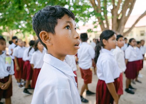 Free A group of children in school uniforms standing attentively outdoors, focusing on an event. Stock Photo