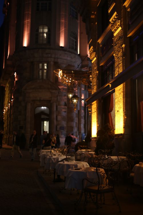 Free Charming city street with elegant outdoor dining tables at night, beautifully lit with warm tones. Stock Photo