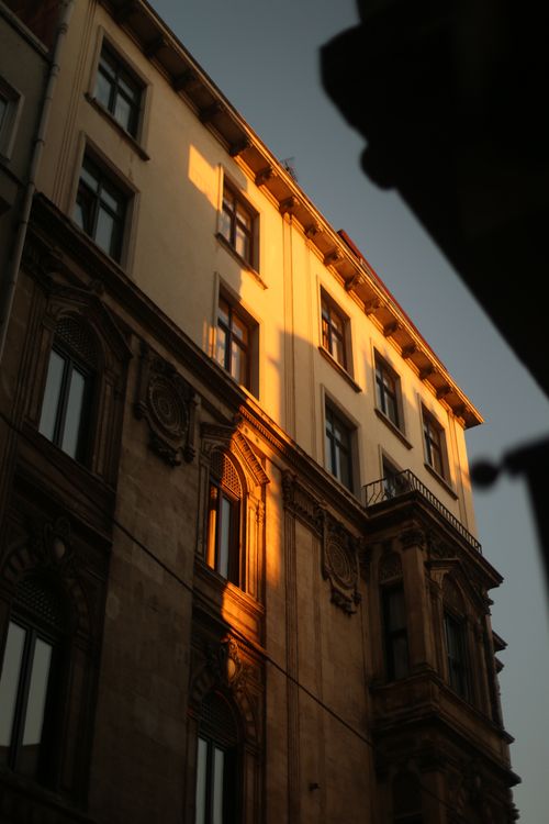 Free A historic building facade beautifully lit by the warm glow of evening sunlight, casting dramatic shadows. Stock Photo