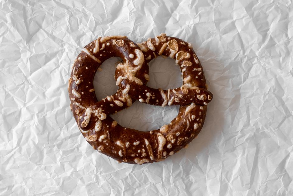 A close-up of a salty pretzel on crumpled white paper, perfect for food photography.