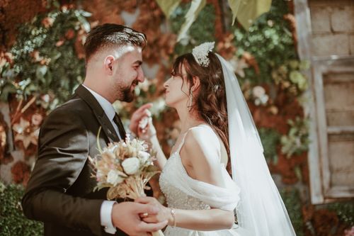 Free A bride and groom share a romantic moment amidst vibrant greenery, capturing their love and special day. Stock Photo