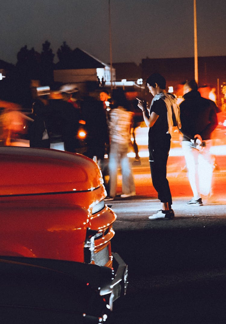 Young Man Looking At Smart Phone On A Night Street