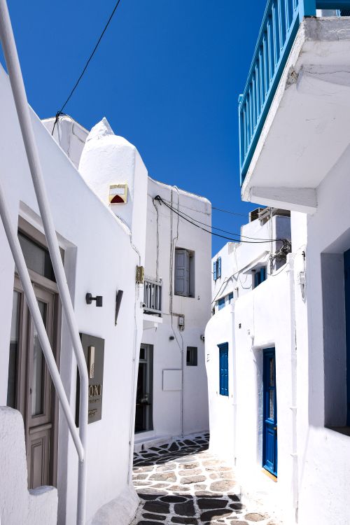 Free Whitewashed buildings line a narrow alley in Santorini, Greece showcasing beautiful Cycladic architecture. Stock Photo