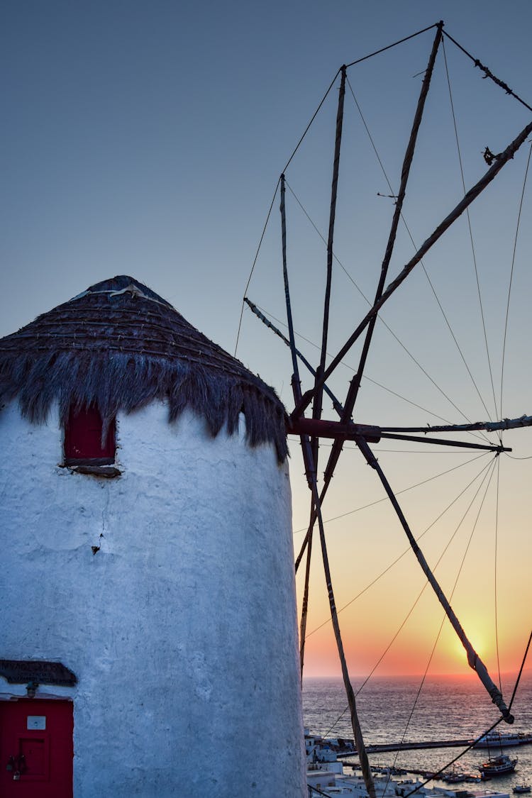 Vintage Windmill On Coast In Town In Greece At Sunset