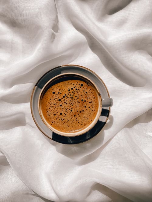 Free Top view of a coffee cup on elegant white fabric, evoking warmth and coziness. Stock Photo