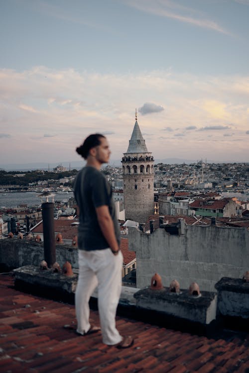 Galata Tower behind Man Standing on Roof in Istanbul