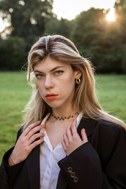 Free Portrait of a blonde woman in a stylish blazer, outdoors in a Berlin park during sunset. Stock Photo