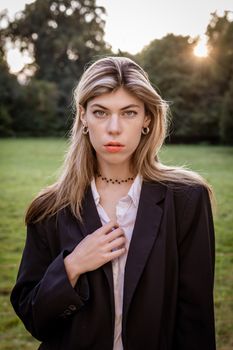 Portrait of a stylish woman in a Berlin park during sunset, showcasing elegance.