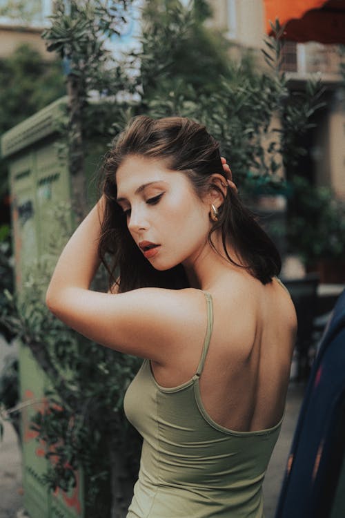 Model in Green Dress Standing and Fixing Hair