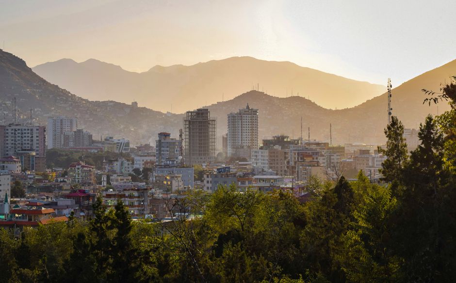 Stunning panoramic view of Kabul, Afghanistan at sunrise, highlighting modern architecture and scenic mountains.