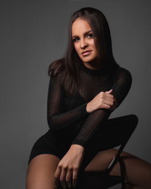 Free Sophisticated portrait of a woman in black attire against a gray background, exuding elegance. Stock Photo
