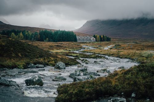 Free Serene landscape with rocks, flowing stream, and distant forest under overcast skies. Stock Photo