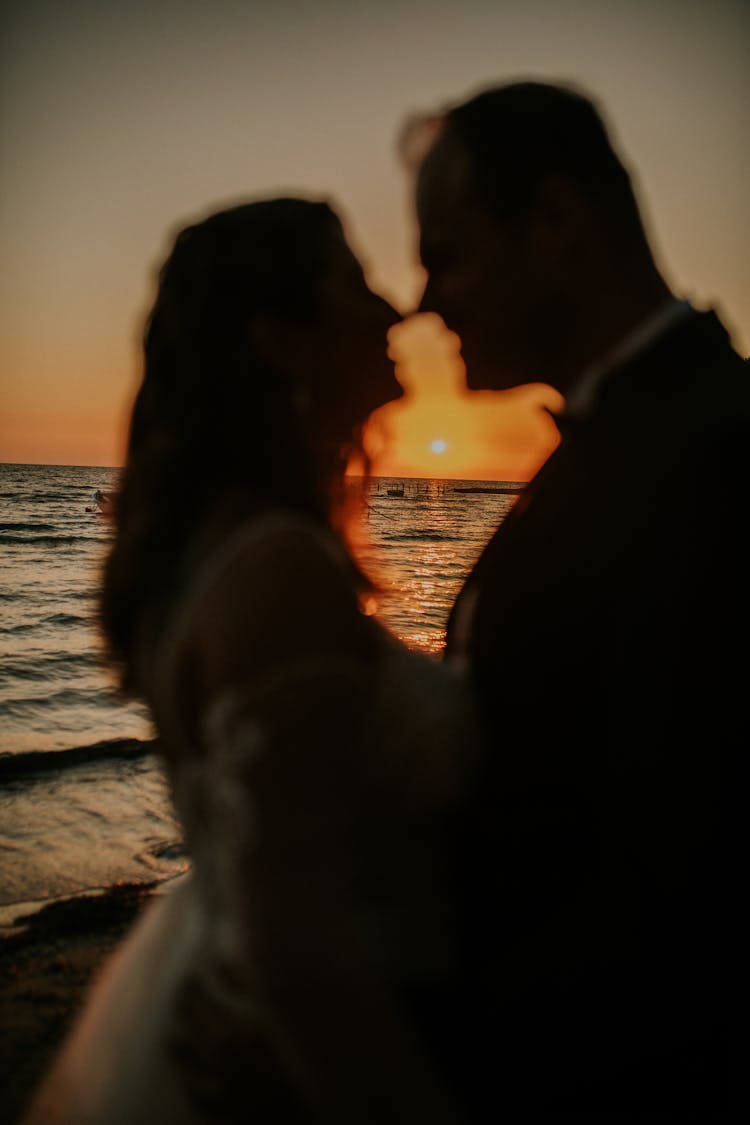 Silhouettes Of Man And Woman Embracing On A Beach At Sunset