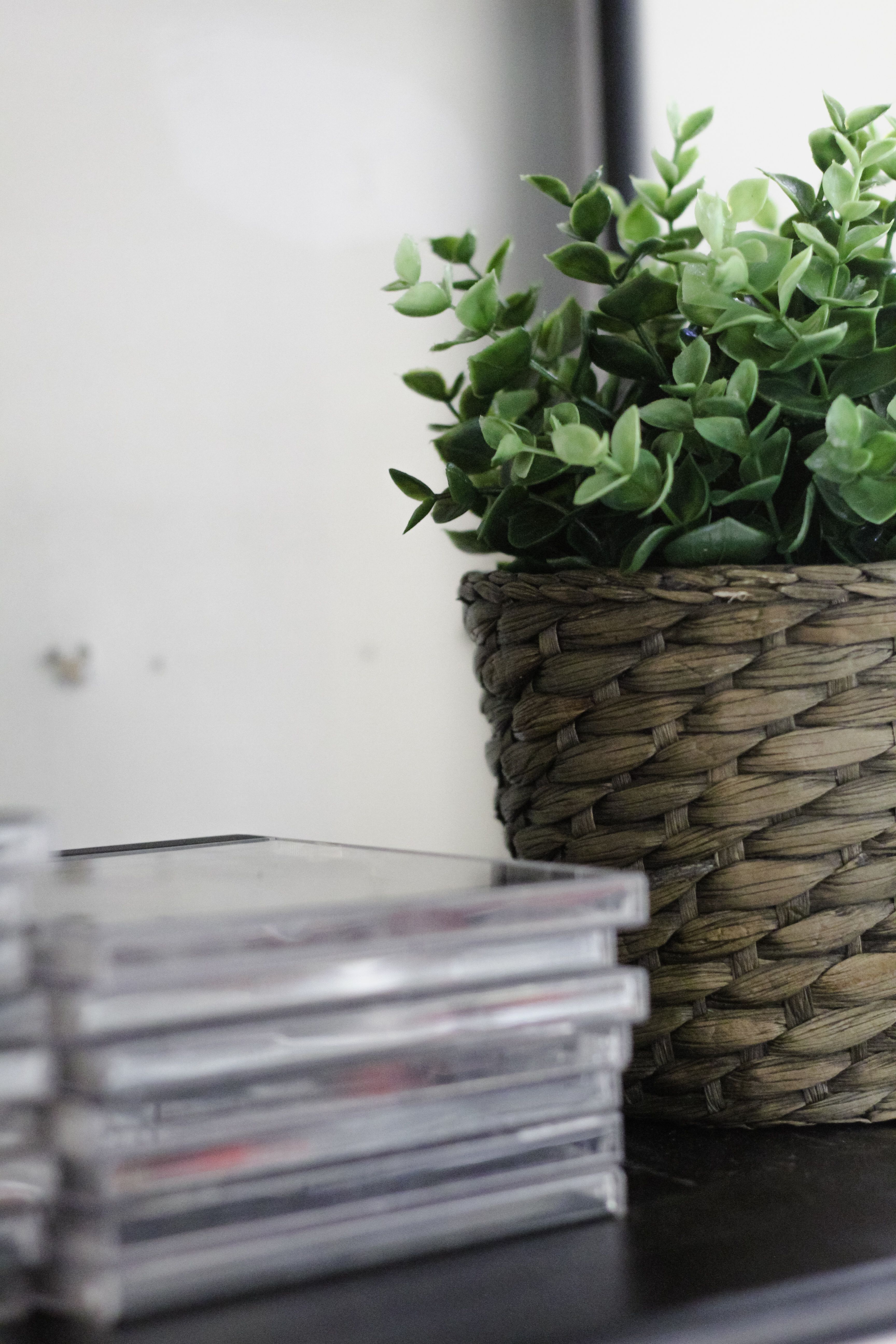 Woven seagrass storage baskets holding extra coffee supplies on open shelving in an office coffee bar