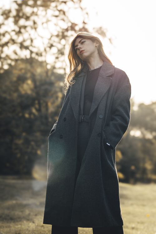 Free Graceful woman in a black coat poses outdoors at sunset, showcasing elegance and style. Stock Photo