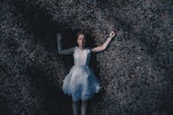 一个女人穿着白衣，躺在草地上，从空中拍摄的艺术画面营造出宁静的氛围