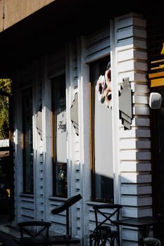 Captivating urban facade with sunlight highlighting details and empty chairs outside a restaurant.