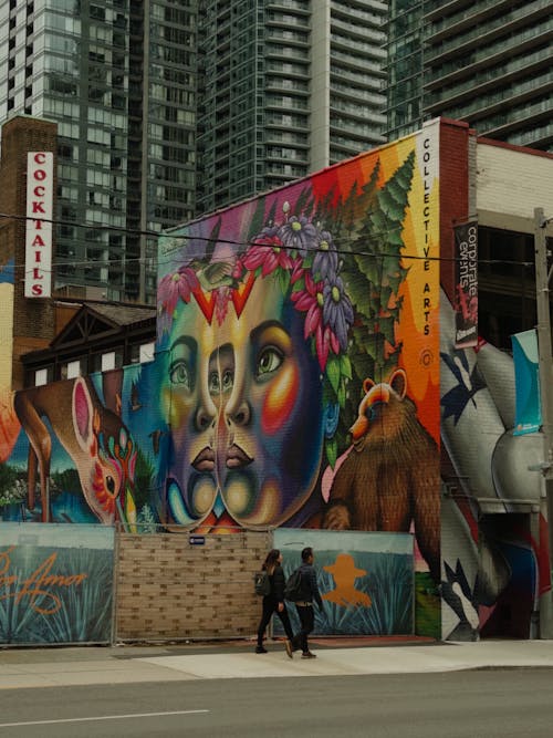 Woman and Man Walking near Mural on Street