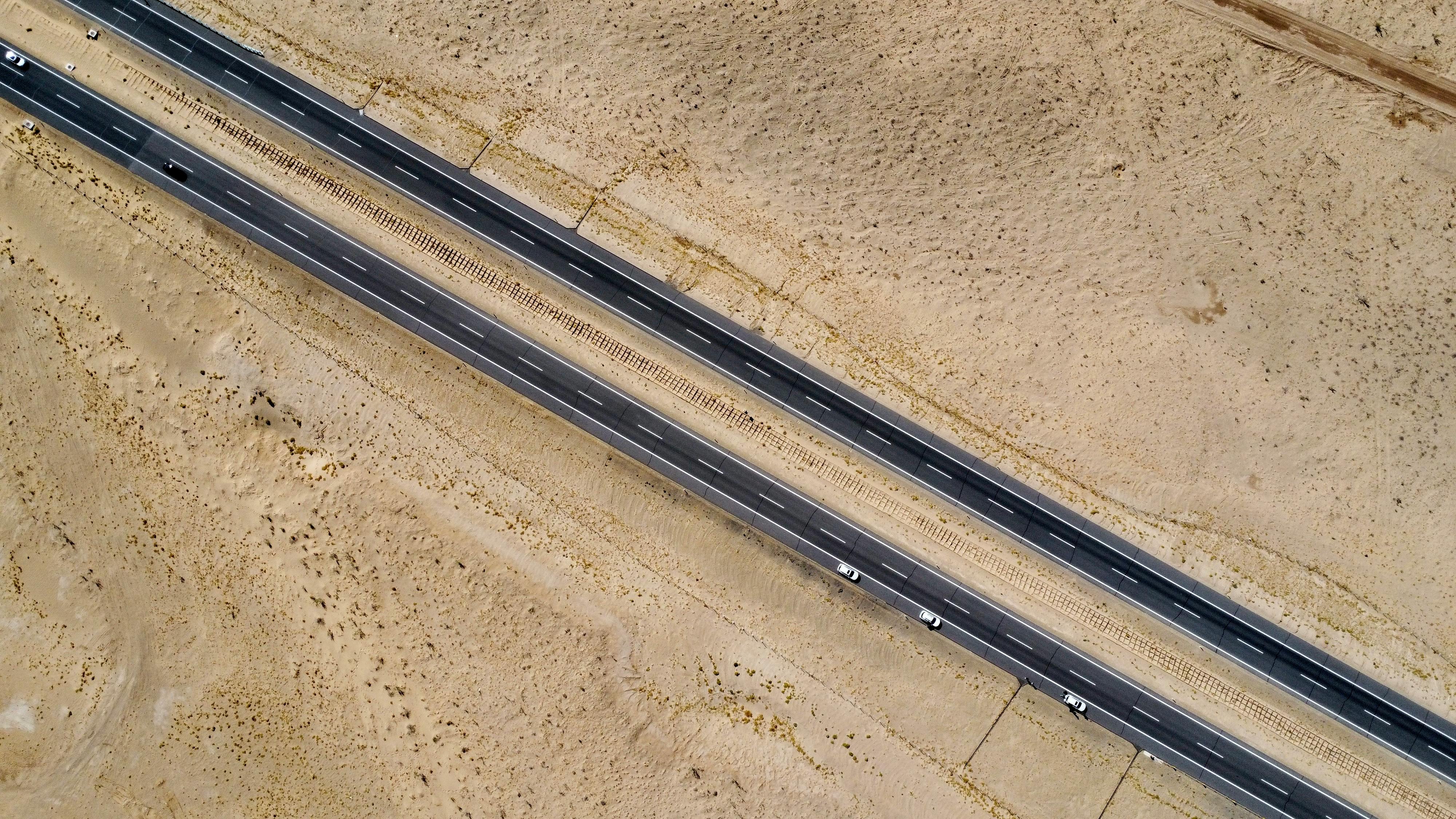 Drone aerial view of a highway cutting through the barren desert landscape in Xinjiang, China.