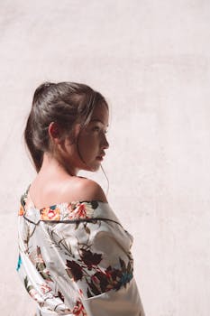 在自然光下，捕捉到一位穿着花卉服装女性的侧面轮廓，凸显优雅