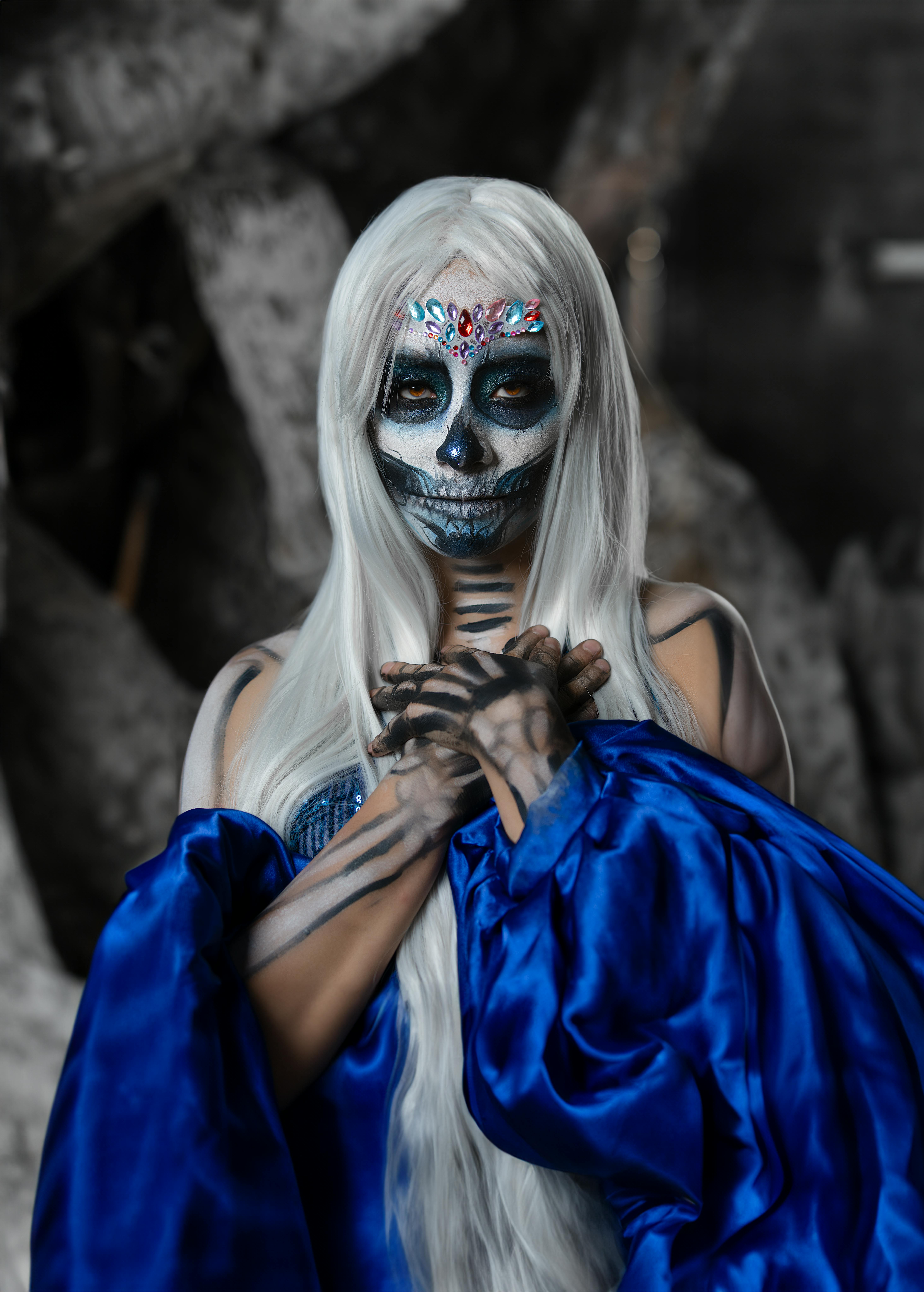 A woman with a Dia de los Muertos painted face in a blue robe, capturing Mexican culture.