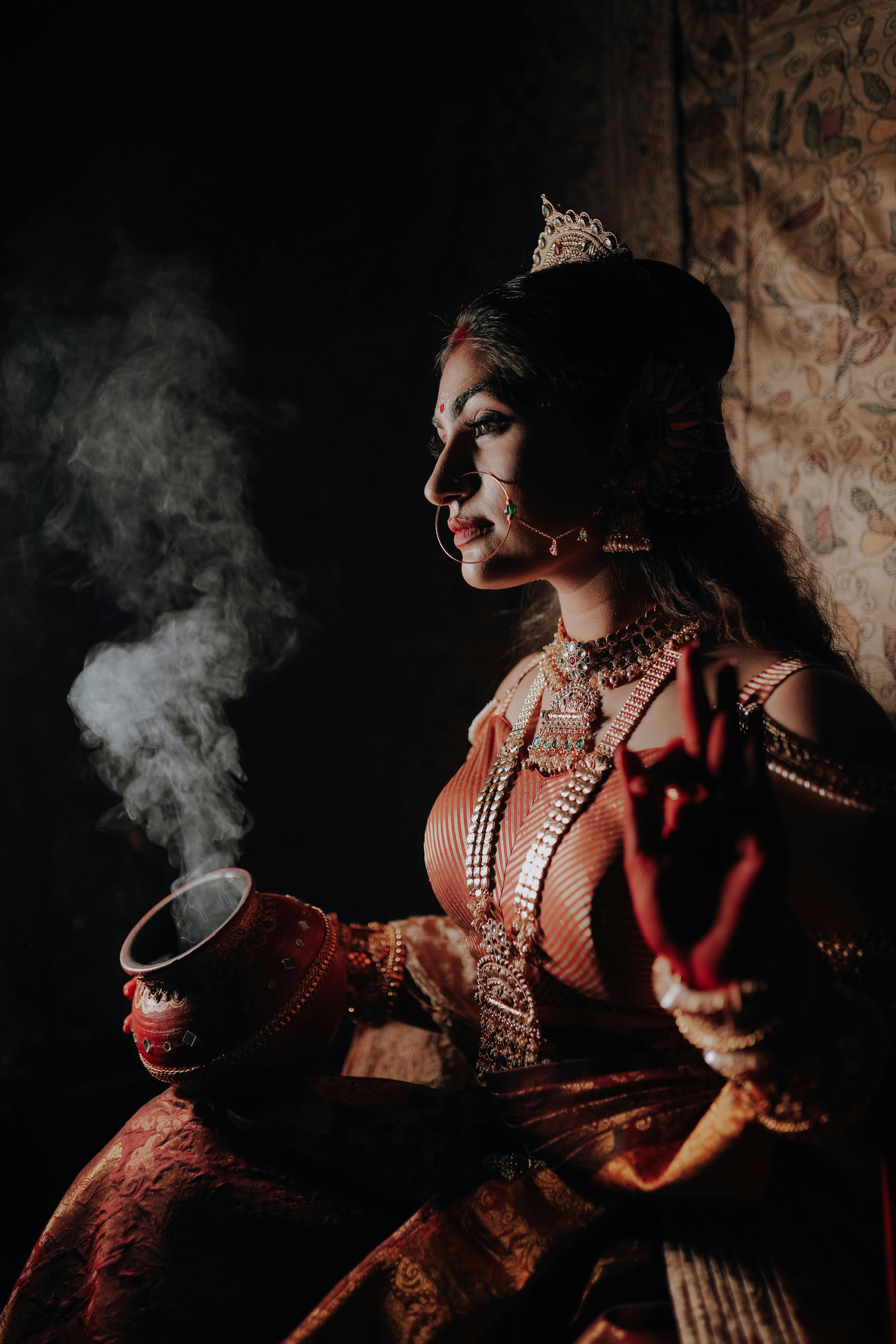 A woman in traditional Indian attire, depicting a goddess, in a dramatic and artistic setting.