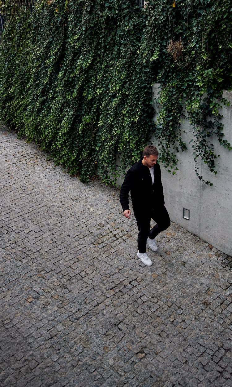 Young Man In Black Shirt And Pants Walking On A Street